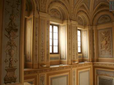 Percorriamo la scala lentamente con l'impressione di entrare "in un altro mondo": il silenzio sostituisce il vocio del viavai sottostante mentre ammiriamo le estese pareti che ci circondano, affrescate con cartigli e festoni dai colori essenzialmente beige e celeste